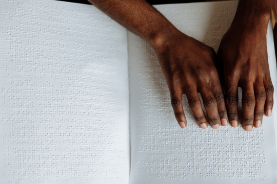 Une paire de mains lisent un livre en braille.
