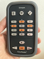 Close shot of a hand holding a Victor Stream player with the front of the device showing.