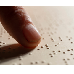 Un doigt qui lit des points saillants de braille.