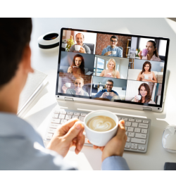 A person sits in front of a laptop which has images of 9 people attending an online meeting.